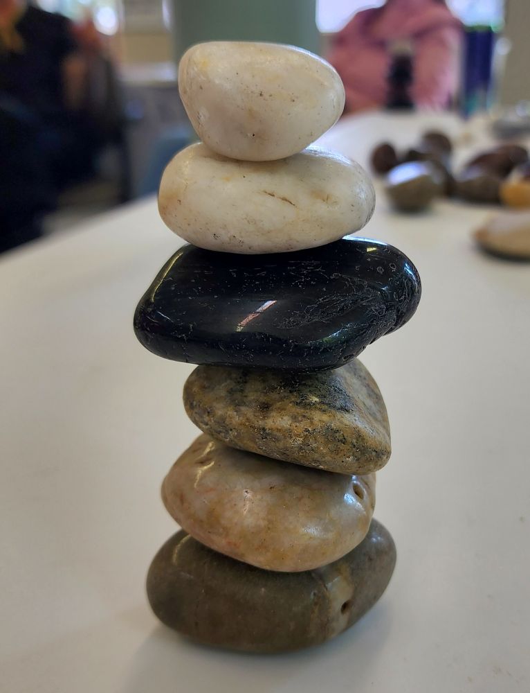 A gray ish rock with a faint white stripe at the bottom, a lighter rock with little flecks in it on top of that, a rock that's a freckled, swirly multicolored one, a black one, and two white ones with tiny freckles