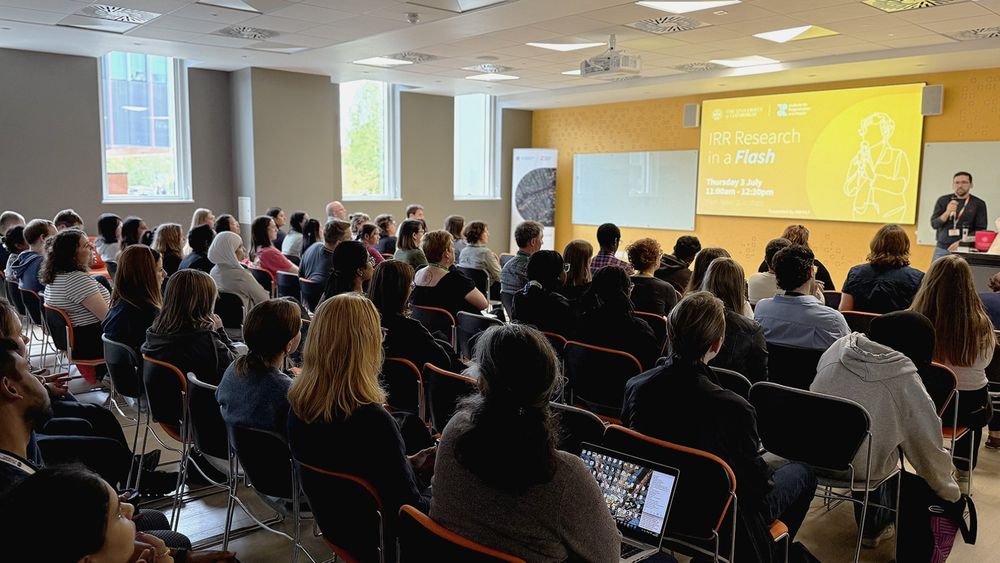 Full seminar room. Man presenting 'research in a flash' presentation