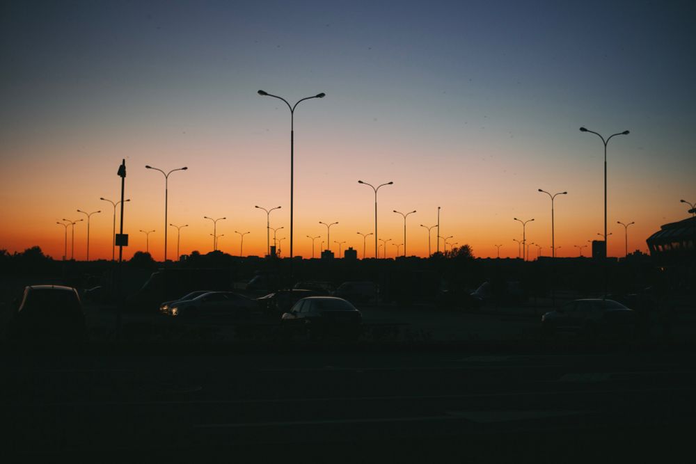Фонарные столбы на парковке на фоне оранжевого заката