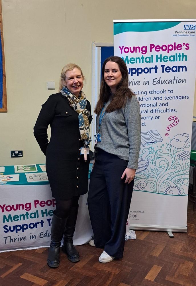 Two individuals standing next to a banner that reads "Young People's Mental Health Support Team.