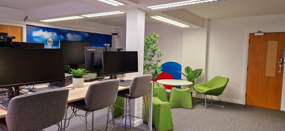 Several computers and chairs in a room, with a mural in the background