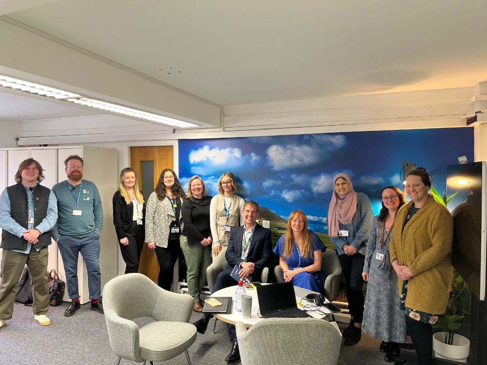 Eleven people standing in front of a mural