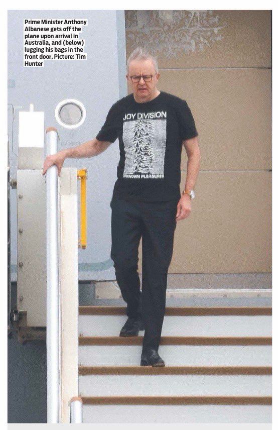 Anthony Albanese, the Australian Prime Minister is pictured walking down the steps of a plane; he is returning from his trip to the USA and looks comfortable and casual in his Joy Division tee-shirt