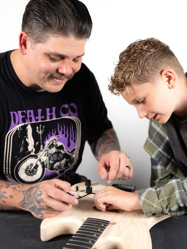 nasty-ass greaser metal dad putting together a guitar kit with his dipshit kid