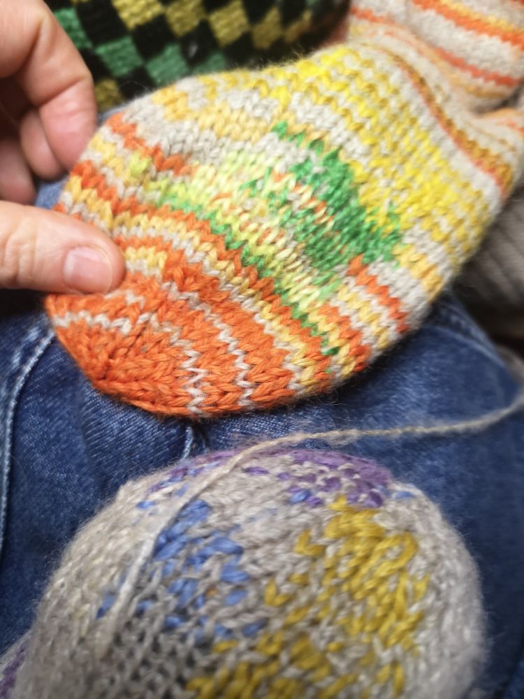 Photo de deux chaussettes de laine visiblement raccommodées avec du fil coloré.