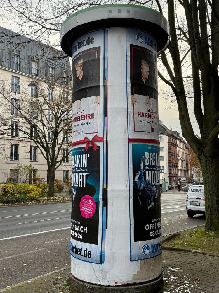 Eine plakatierte Litfaßsäule an einer Straße 