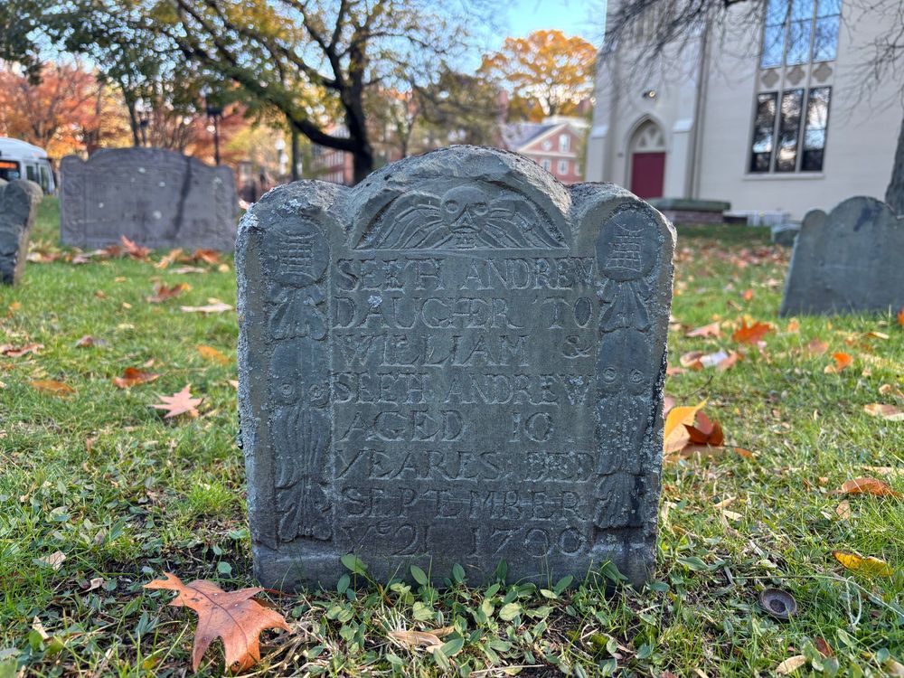A gravestone, in shadow, hard to read 