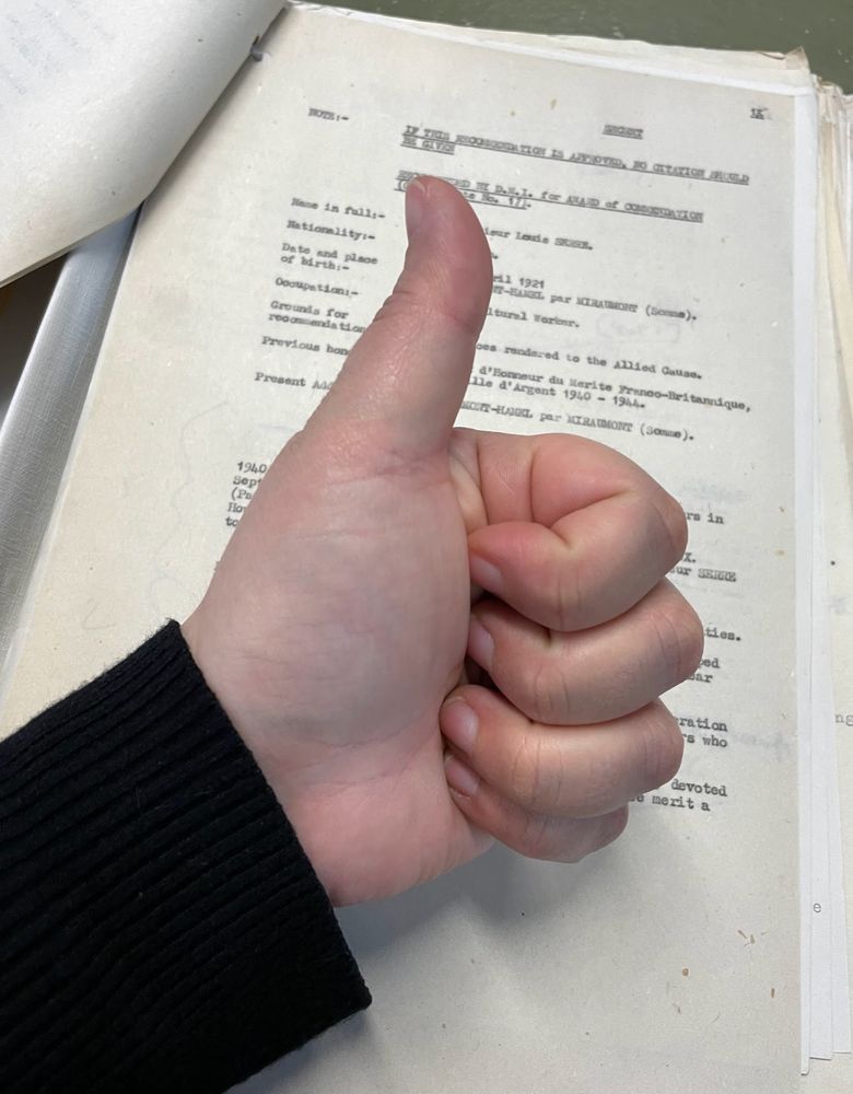 photo of my hand giving a thumbs up to an archival document