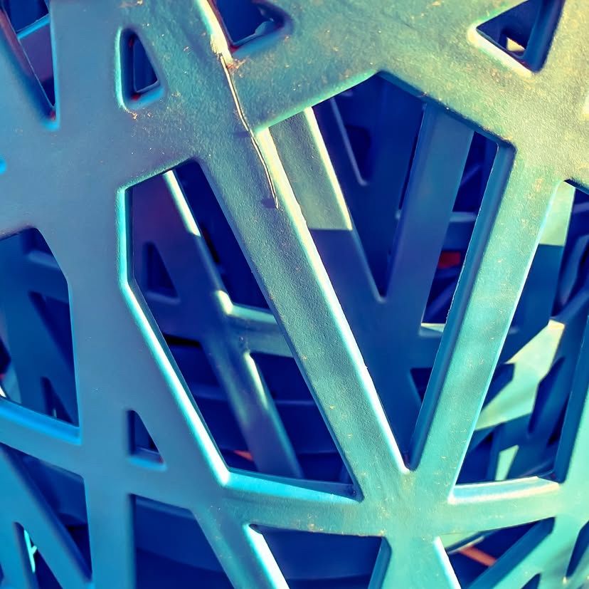 cropped view of the back of a stack of blue plastic lattice outdoor chairs