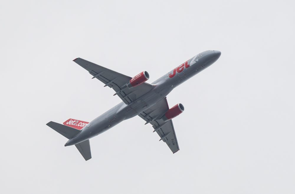 A grey twin-engined passenger jet against grey skies, set off by red engine cowls and a red tail