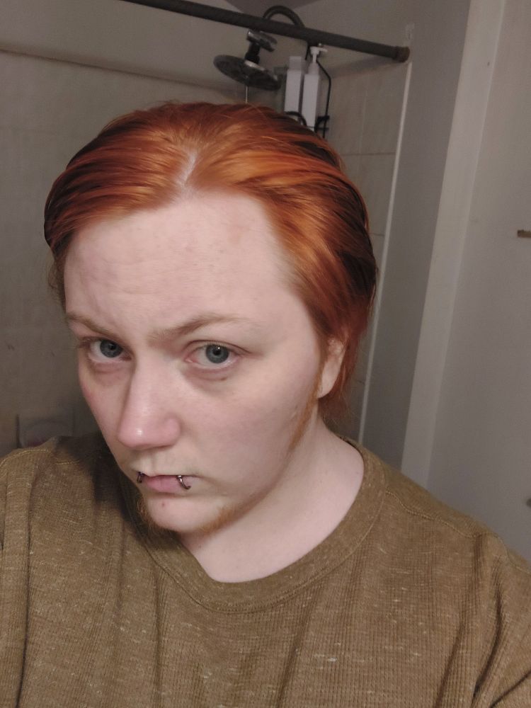 A picture of me right out if the shower, my bright orange hair brushed back. I am facing to the left again. This time I am not wearing glasses or a jacket, I have an olive green shirt on