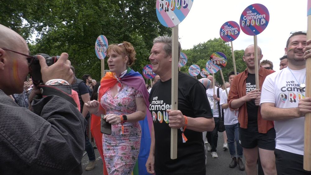 Picture of Keir Starmer at pride holding a sign with the trans pride flag on it. 