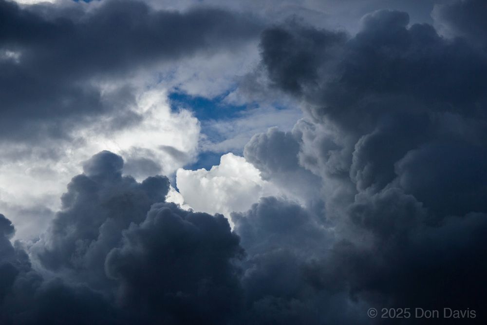 This photo shows brightly lit cumulus clouds in the background lighting up the edges of the nearer shaded clouds, 