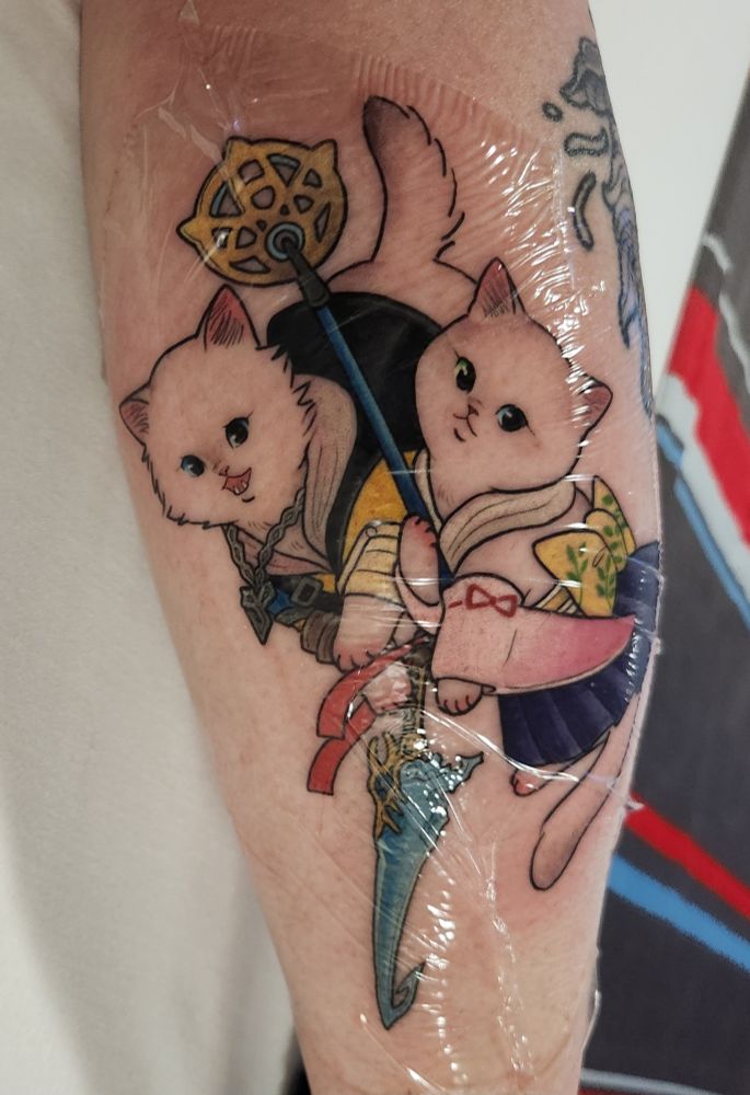 a tattoo of two vintage style illustrated cats who are dressed as tidus and yuna from final fantasy x. yuna is holding her staff and tidus is holding the sword brotherhood.