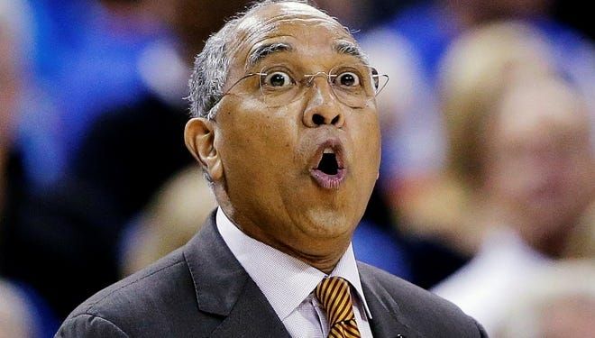 Basketball coach, Tubby Smith, is pictured with his mouth puckered in an "O" shape while looking towards the camera,. presumably calling to a player or referee.