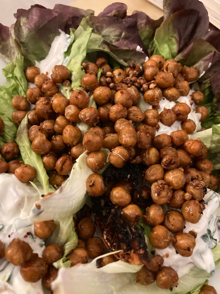 Photo en gros plan de pois chiches rôtis sur un lit de salade verte avec de la sauce au fromage blanc de chèvre 