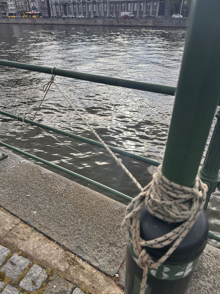 Corde attachée à un poteau et une barrière. La corde plonge ensuite dans l’eau.
