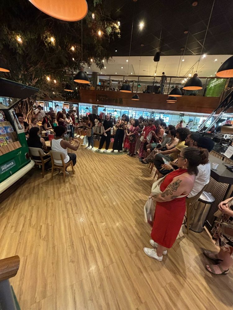 foto em grande angular mostrando o público em pé e sentado ao redor da mesa