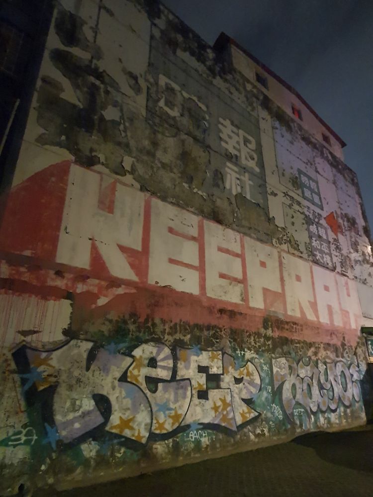 A giant set of tags spanning the width of an old building; both read "KEEPRAY" but in very different styles.