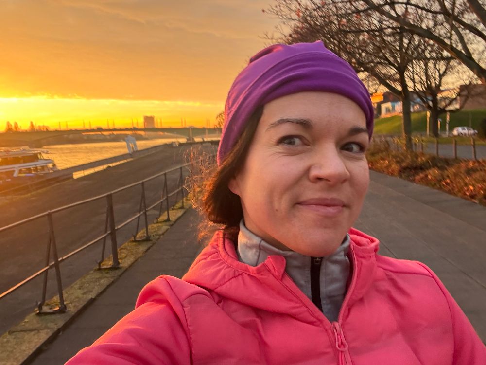 Selfie laufend am Rhein mit orange-gelbem Sonnenaufgangshimmel
