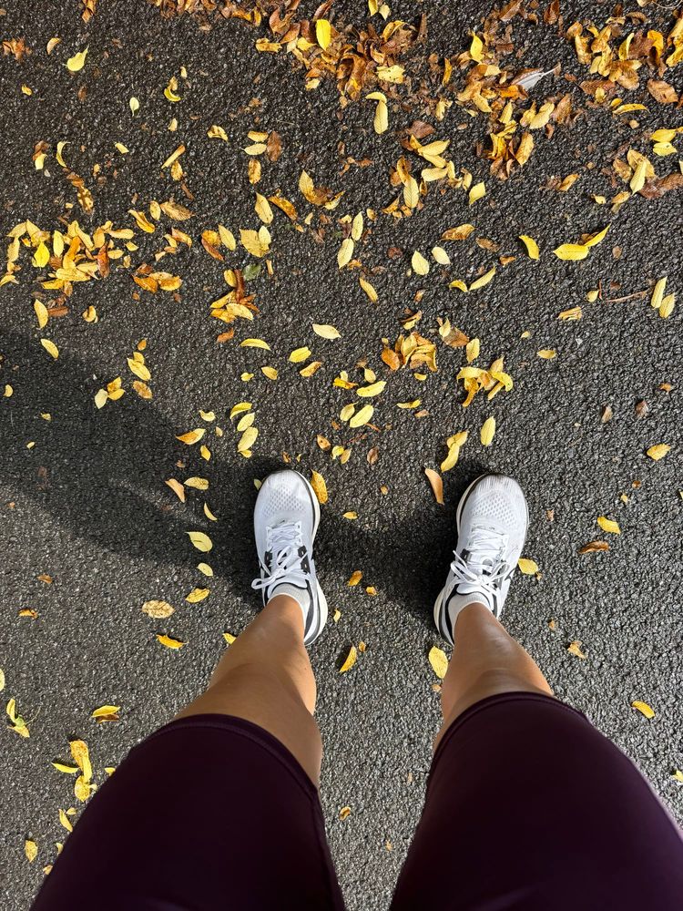 POV ich in Laufklamotten auf Asphalt, umgeben von kleinen gelben Blättern.