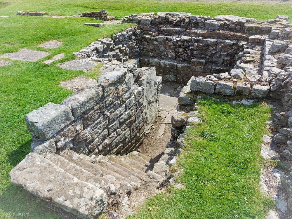 The remains of an underground strongroom, reached by a short staircase. Little survives above ground level, but the stonework set into the ground looks very robust.