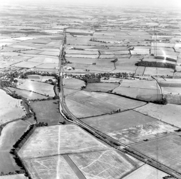 A black and white aerial photograph showing a broad agricultural landscape, divided by enclosure hedges. Villages and hamlets are dotted about, connected by lanes. The large features are described in the main post.

Cambridge University Aerial photo collection, CUCAP BYM96.
