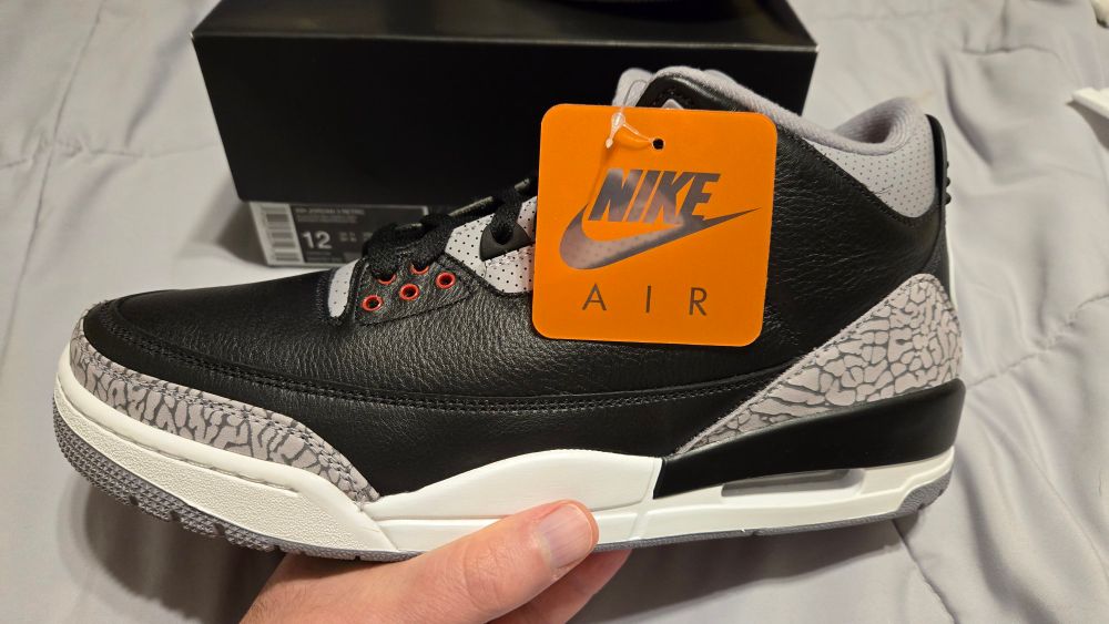Jordan 3 OG Retro shoe. White, black, gray, red shoe with orange tag that says Nike Air
