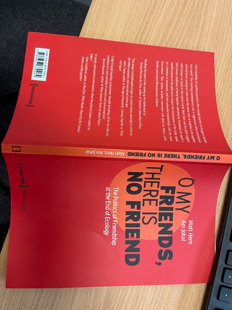 Red book on a light wooden desk, black keyboard visible off shot. 