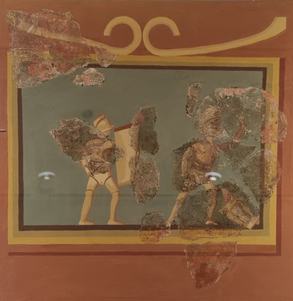 Fragments of a Roman mosaic showing two gladiators in combat, with lots of modern restoration.
