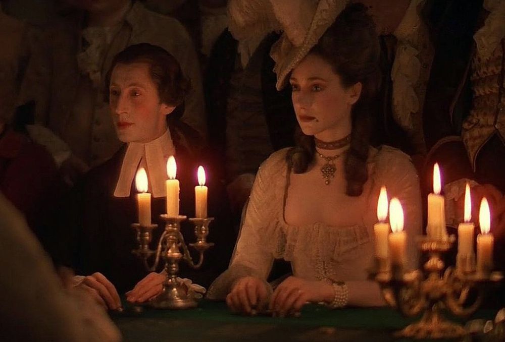 A candle-lit scene from the movie Barrie Lyndon, with two of the characters sitting at a table next to two candelabra.