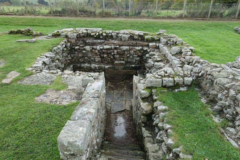 The ruins of an underground chamber, now roofless, with a paved stone floor.