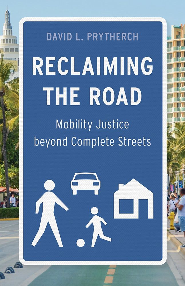 Cover of Reclaiming the Road: Mobility Justice beyond Complete Streets by David L. Prytherch. Set against a photo of bike lane, the title text is made to appear as a blue traffic caution sign with white silhouettes of people and objects below.