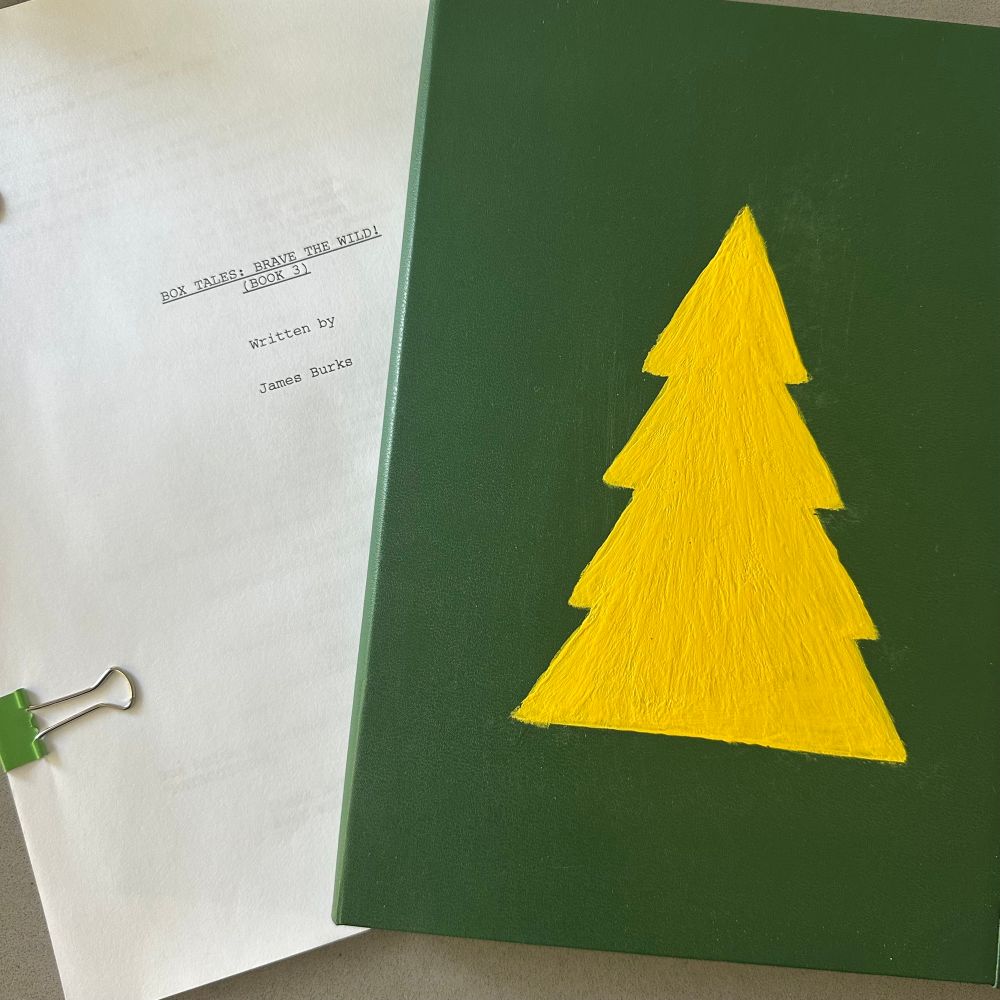 A green sketchbook with a yellow painted tree on the cover. 