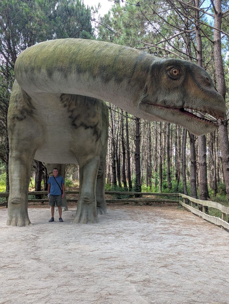 My husband is standing under a large dinosaur.