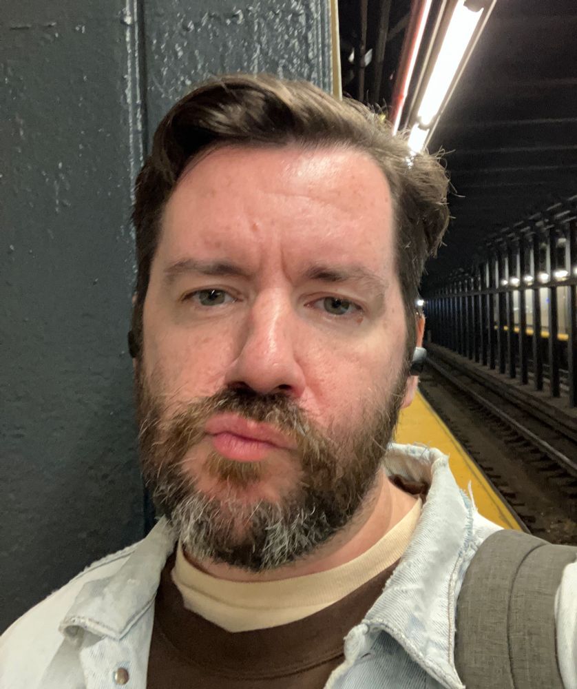 A selfie in a subway station, still unsmiling, lips skewed to the side and pooched out a little.