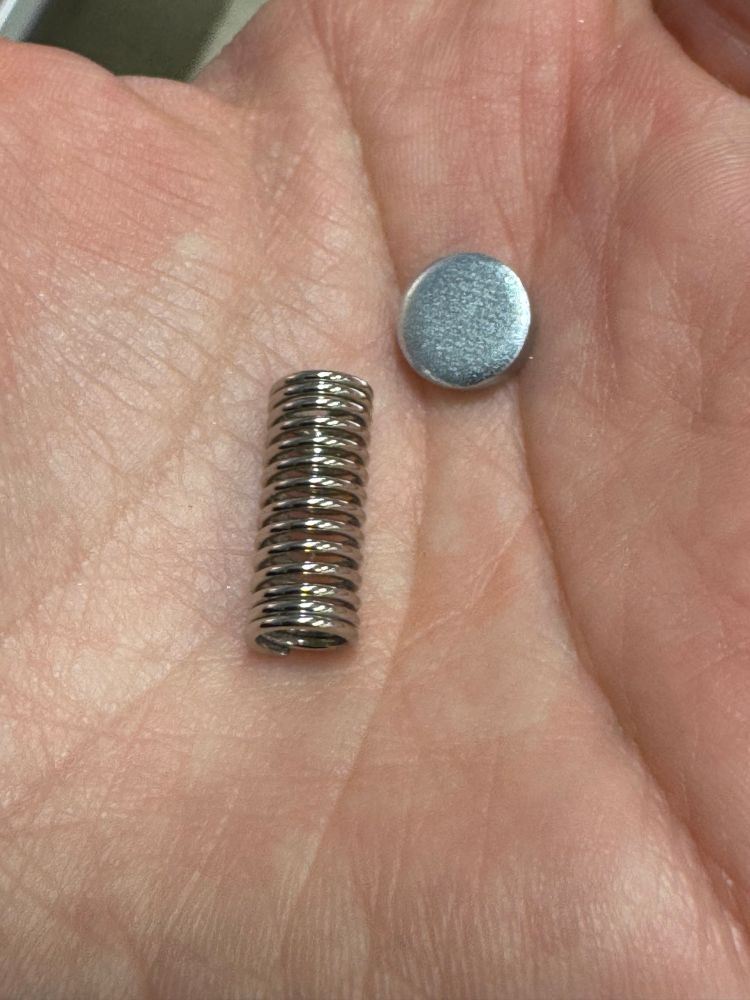 En bild på en metallspiral och en metallplupp i min handflata 