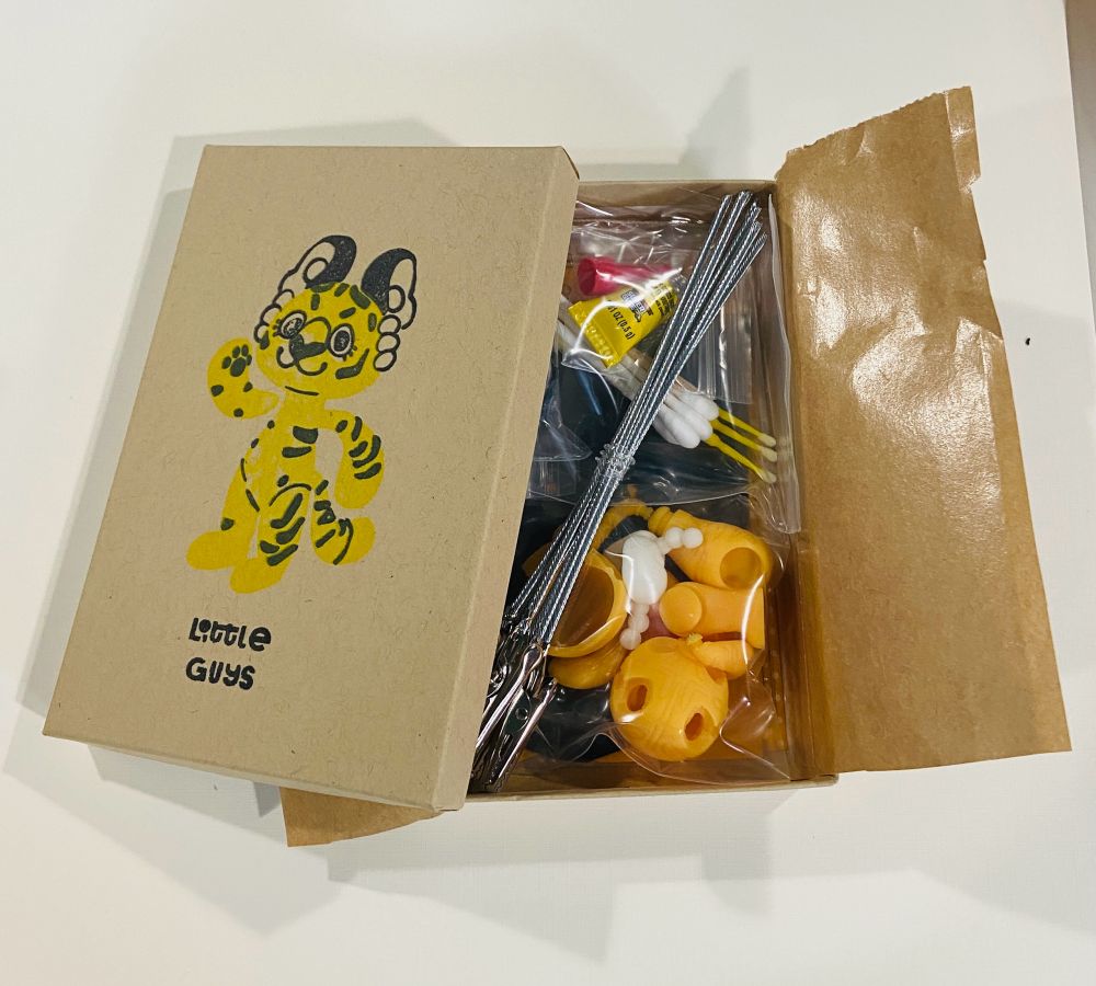 A Kraft paper box with a tiger stamped on the front, halfway open revealing the pieces of a make your own tiger kit inside 