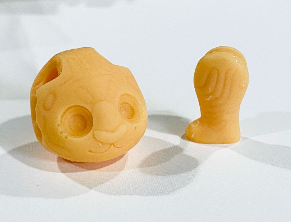 A close up shot of an unpainted tiger head without ears, and a leg, showing the marking details that are part of the model sculpt 
