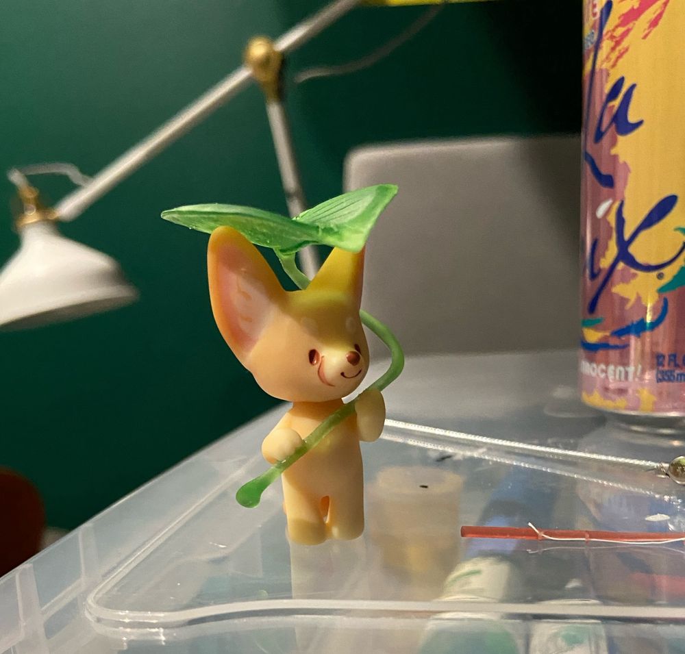 A fennec Fox figurine holding a translucent giant (to him) leaf sorta like an umbrella. 