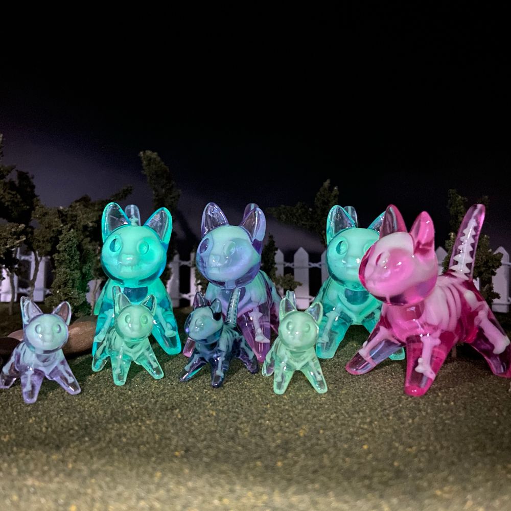 A group of dimly-lit glowing skelly cats, both big and small 