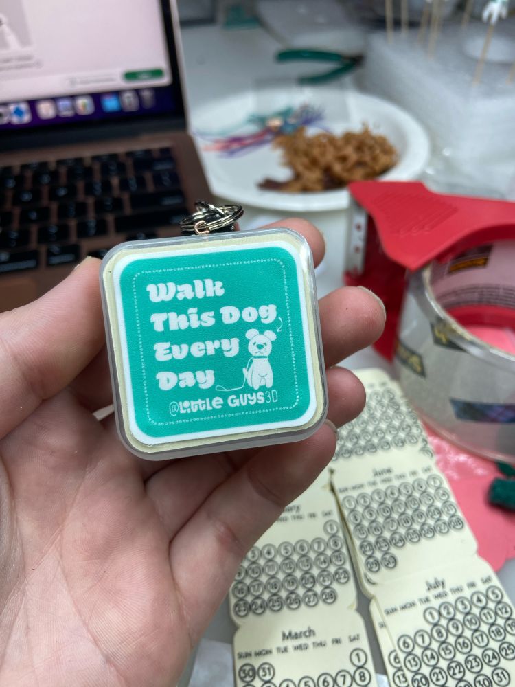 A keychain container with a label that says “walk this dog every day”