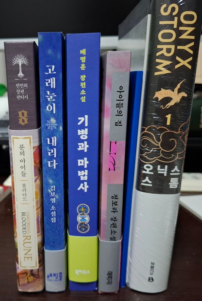 책『룬의 아이들 블러디드 8』, 『고래눈이 내리다』, 『기병과 마법사』, 『아이들의 집』, 『오닉스 스톰 1』의 실물사진
