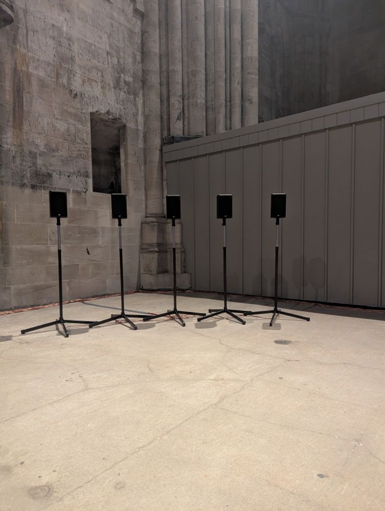 5 black speakers in a section of church that is under construction. There are 35 more speakers out of frame. Each is playing a different voice in Spem in Allium by Tallis.
This is "the 40 part motet" by Janet Cardiff