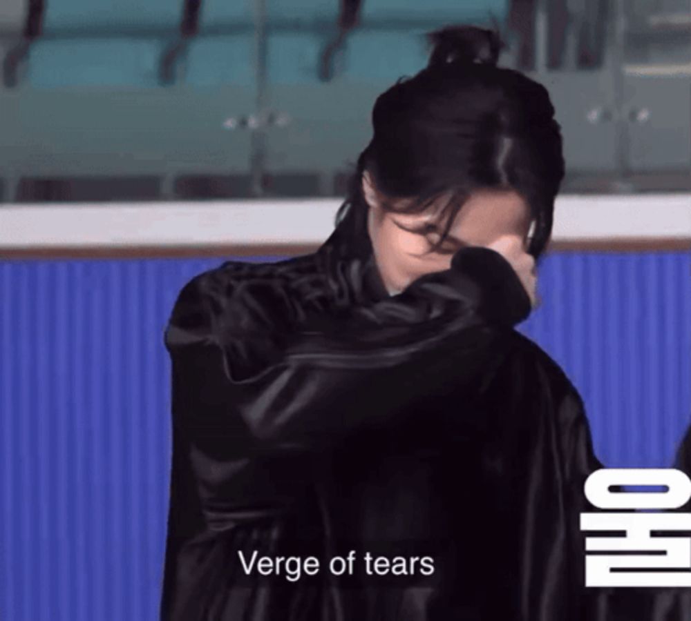 a woman in a black jacket is covering her face with her hand and the words verge of tears are below her