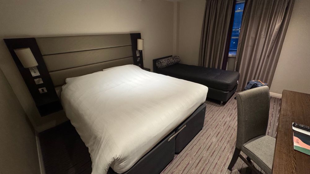 A hotel room with a large kings size bed and a single bed next to it 