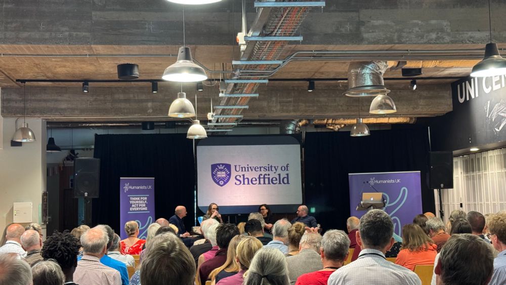 A picture of the panelists at a distance with many people sitting ahead of them 