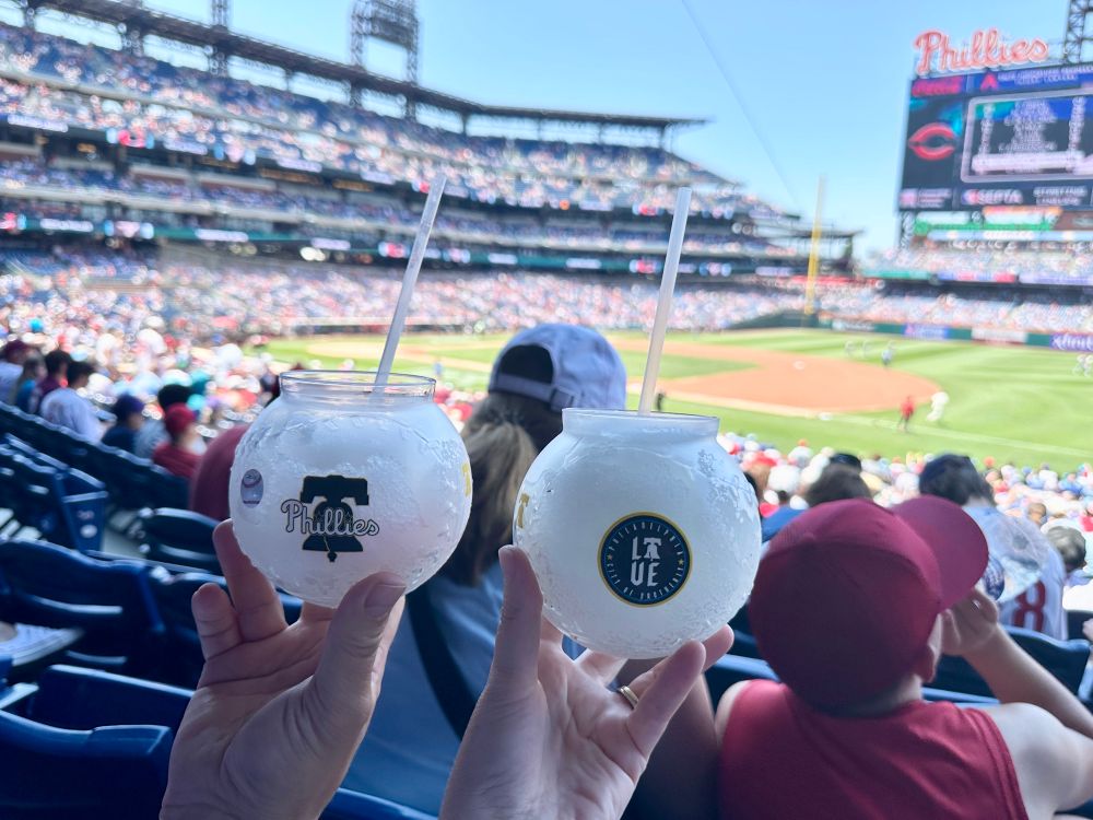 Two frozen margaritas being held with the baseball field of Citizen’s Bank Park in the background.