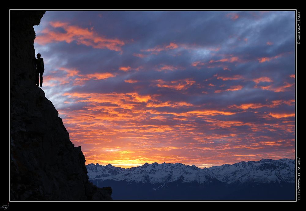 randonneur sur une vire étroite à contre-jour sur une falaise, sur fond de ciel en feu