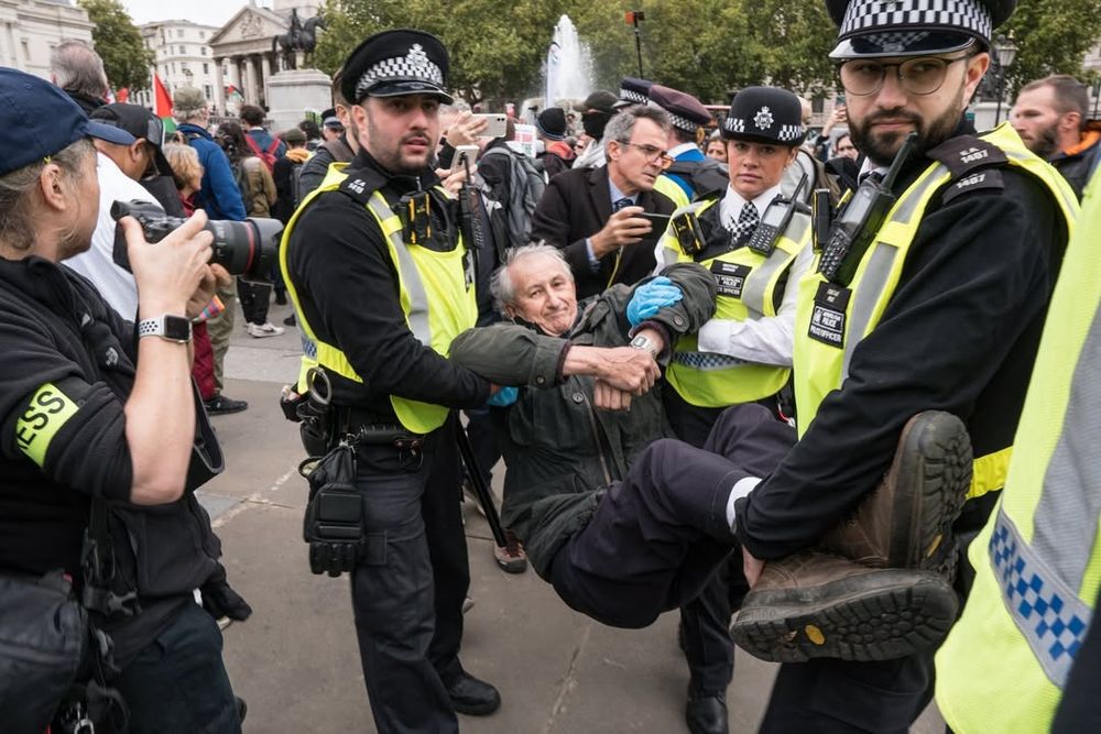 Lifting an anti-genocide protester in Trafalgar Square. 